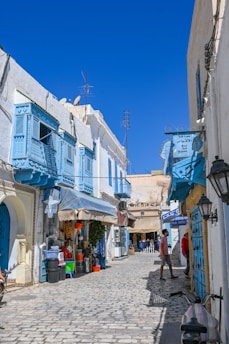 Cobblestone street lined with shops and blue balconies.