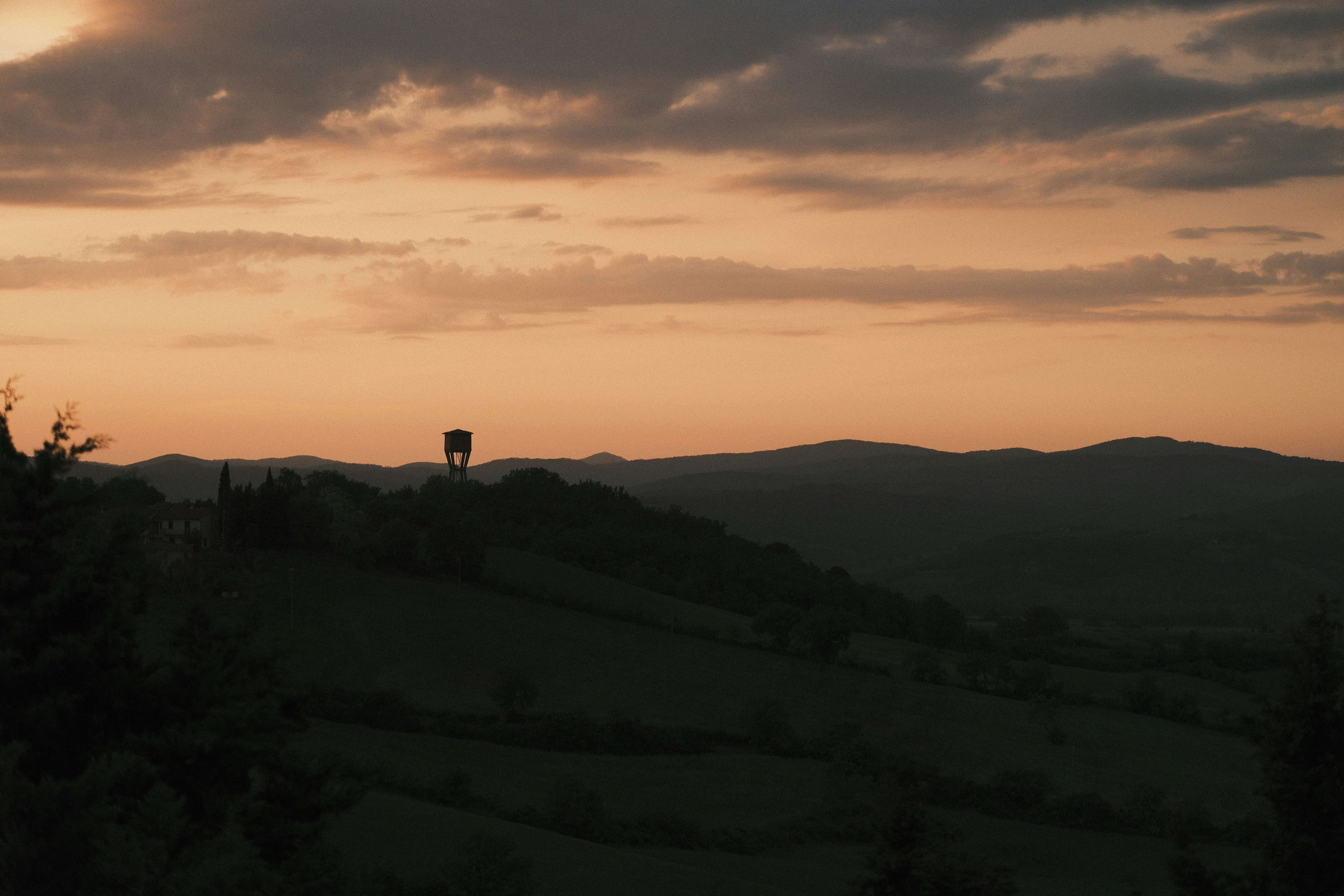 Sunset paints the sky over a hilly landscape.