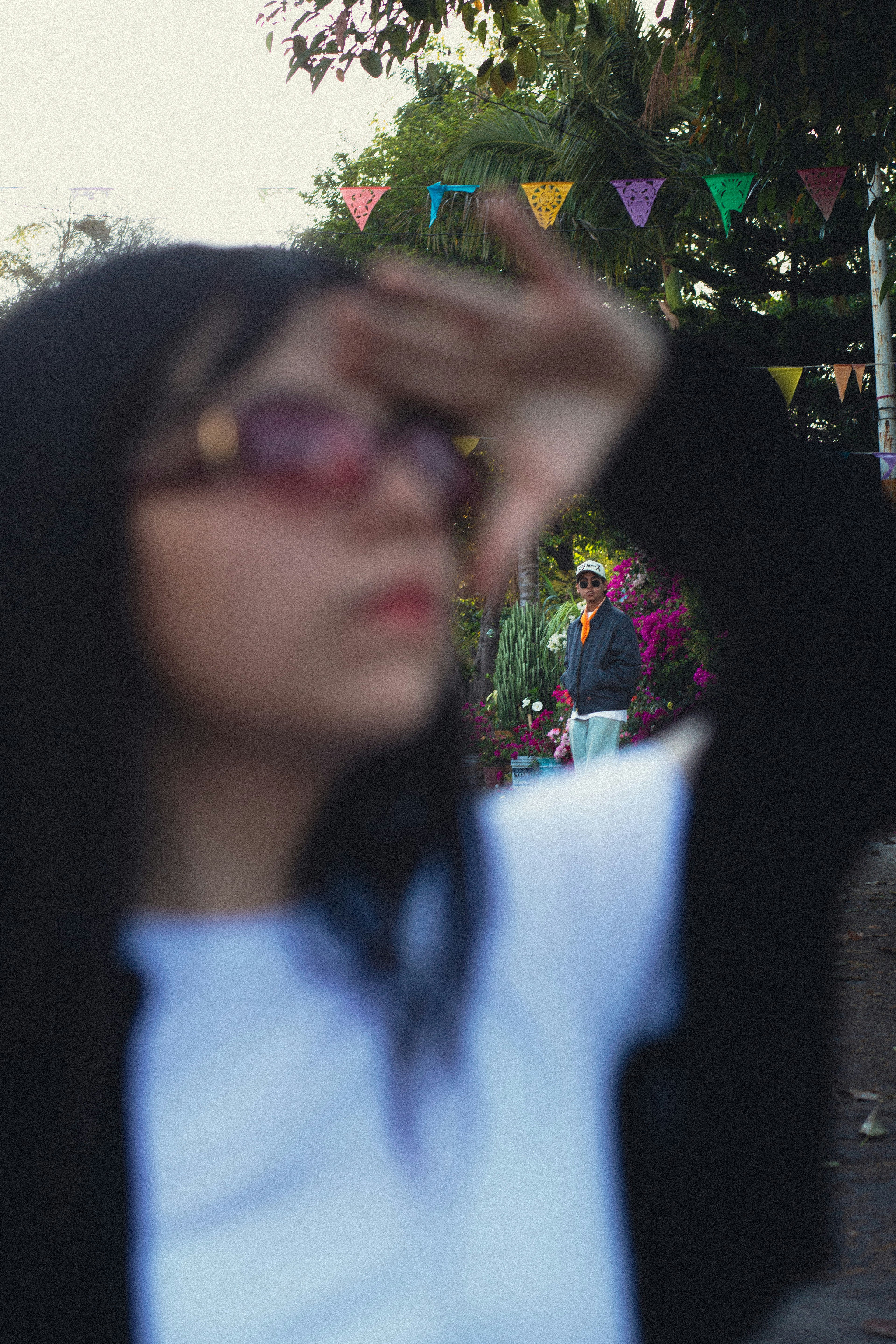 Young woman shielding eyes, man in background.