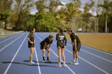 Four athletes in black on a blue running track