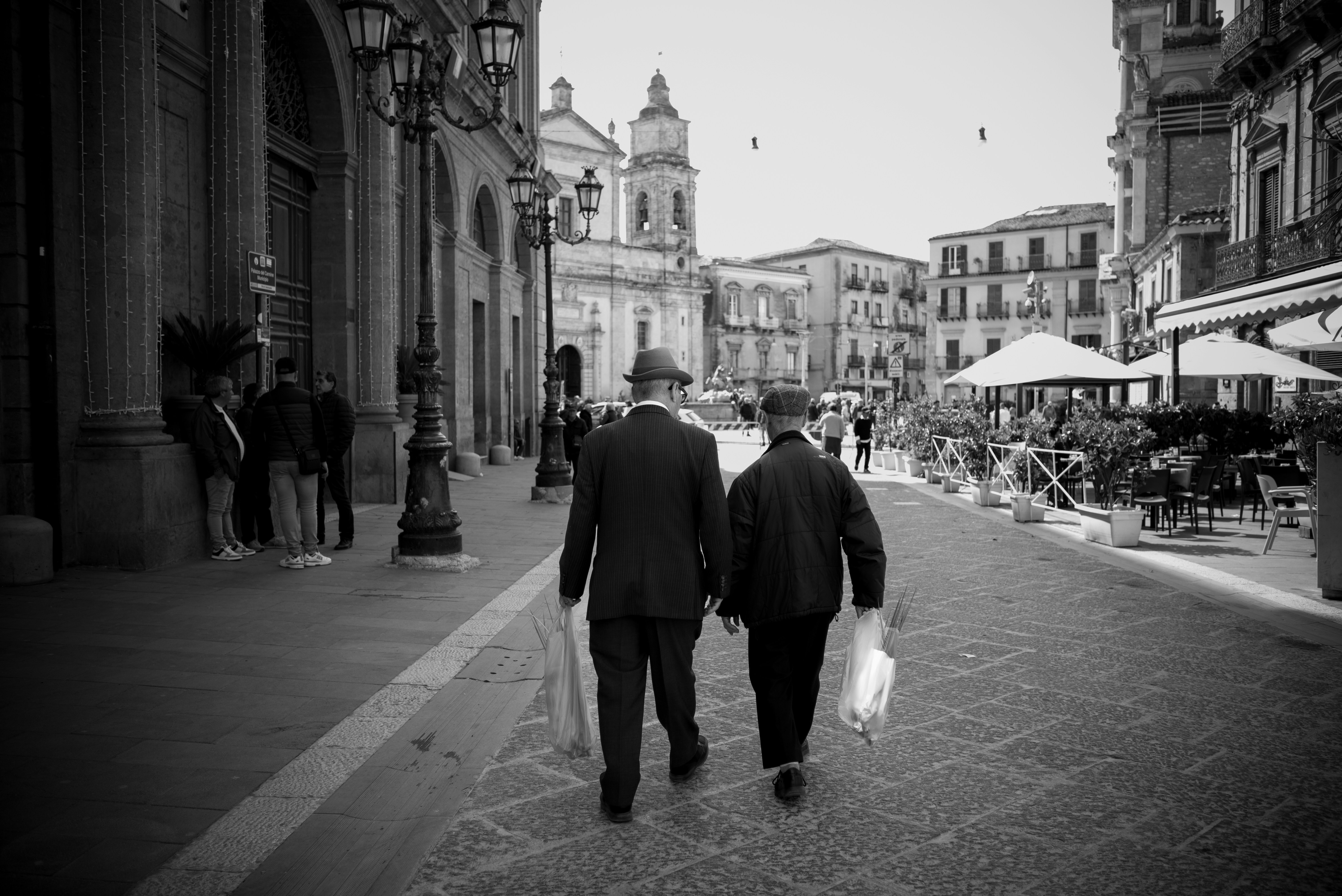 Two men walk down a street, captured in black and white.