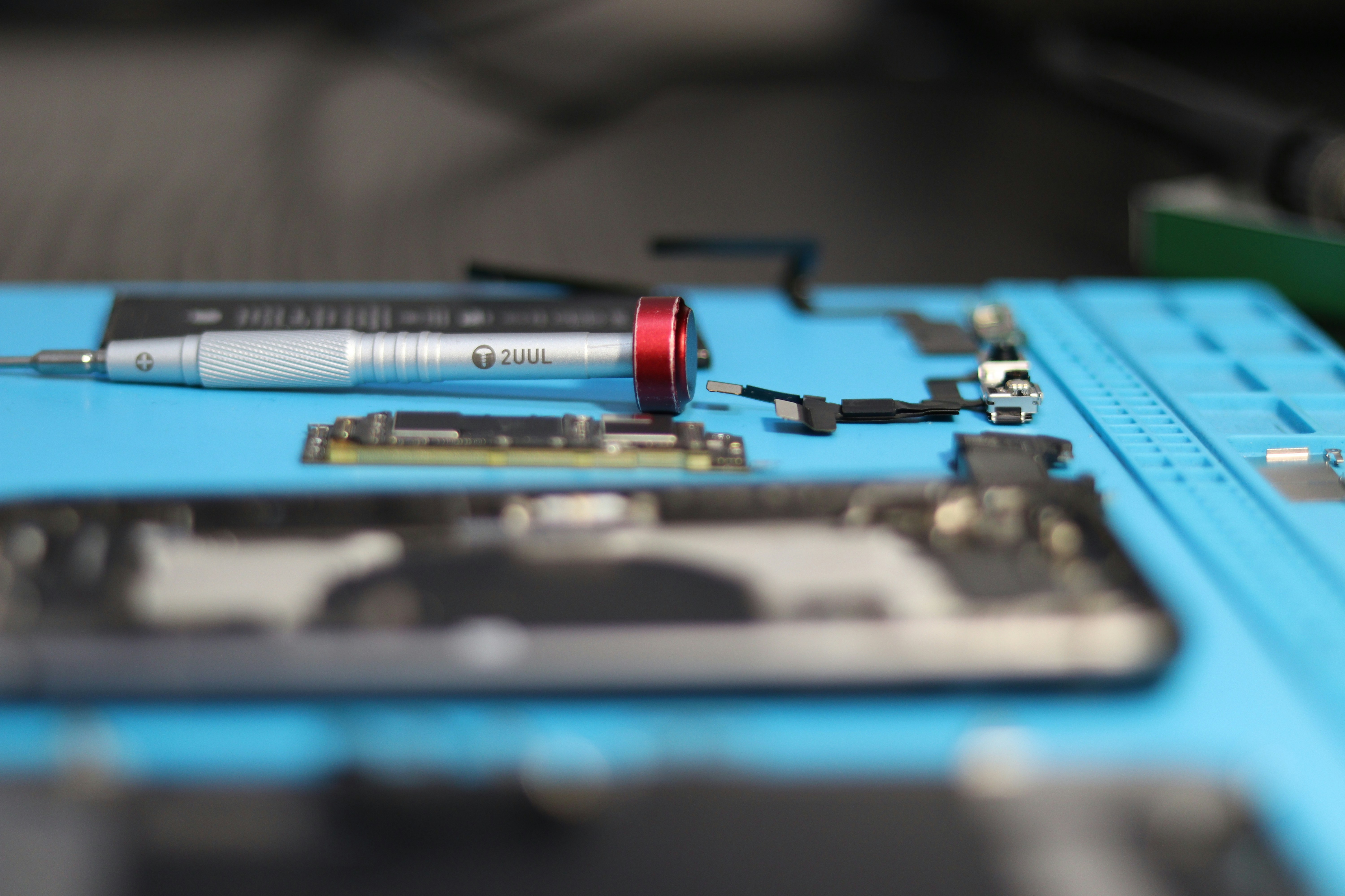 Phone repair tools lay on a blue mat.