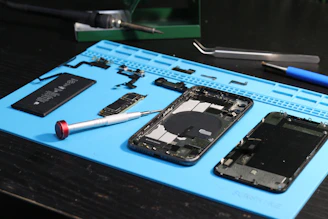 Componentes e ferramentas para reparo de telefones estão dispostos ao redor.