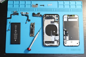 iPhone components are disassembled on a blue mat.