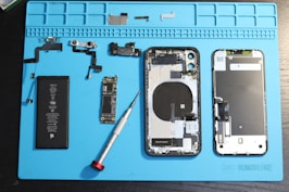 iPhone components are disassembled on a blue mat.