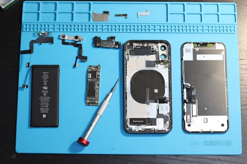 iPhone components are disassembled on a blue mat.