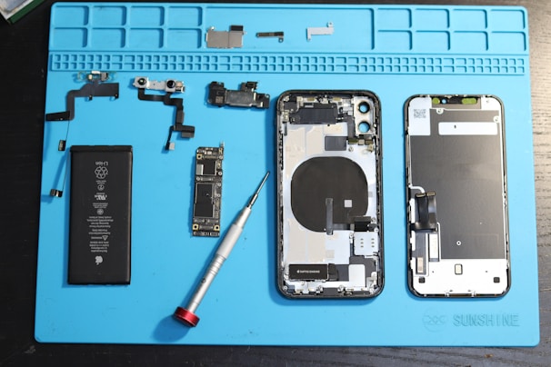 iPhone components are disassembled on a blue mat.