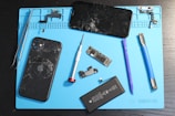 A disassembled iPhone and repair tools on a mat.