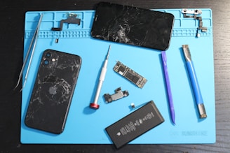 A disassembled iPhone and repair tools on a mat.