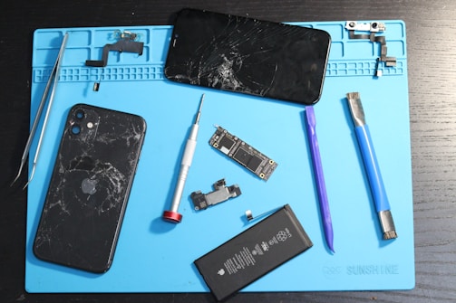 Broken iPhone parts are laid out on a mat.
