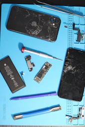 Broken phones with parts and repair tools.