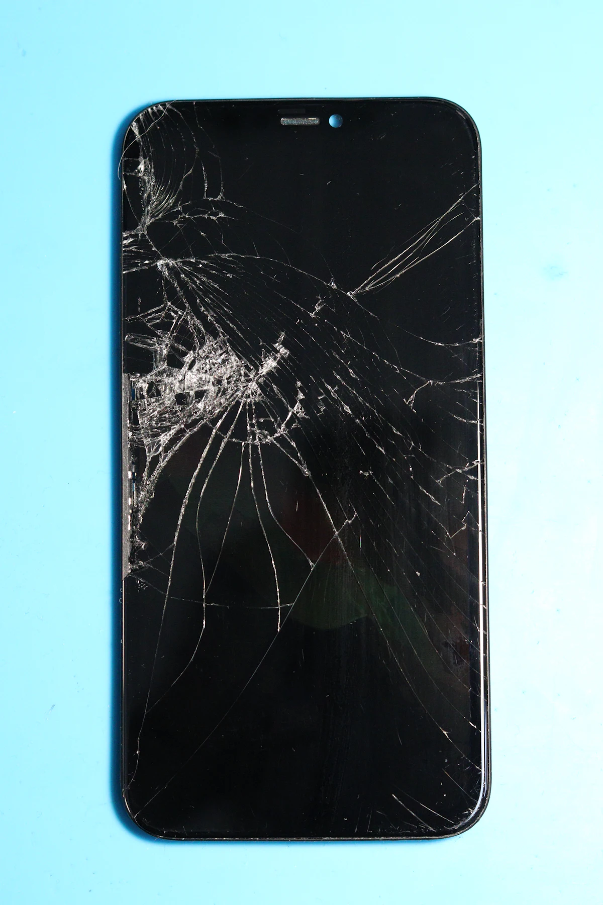 Écran de smartphone cassé posé sur une surface bleue