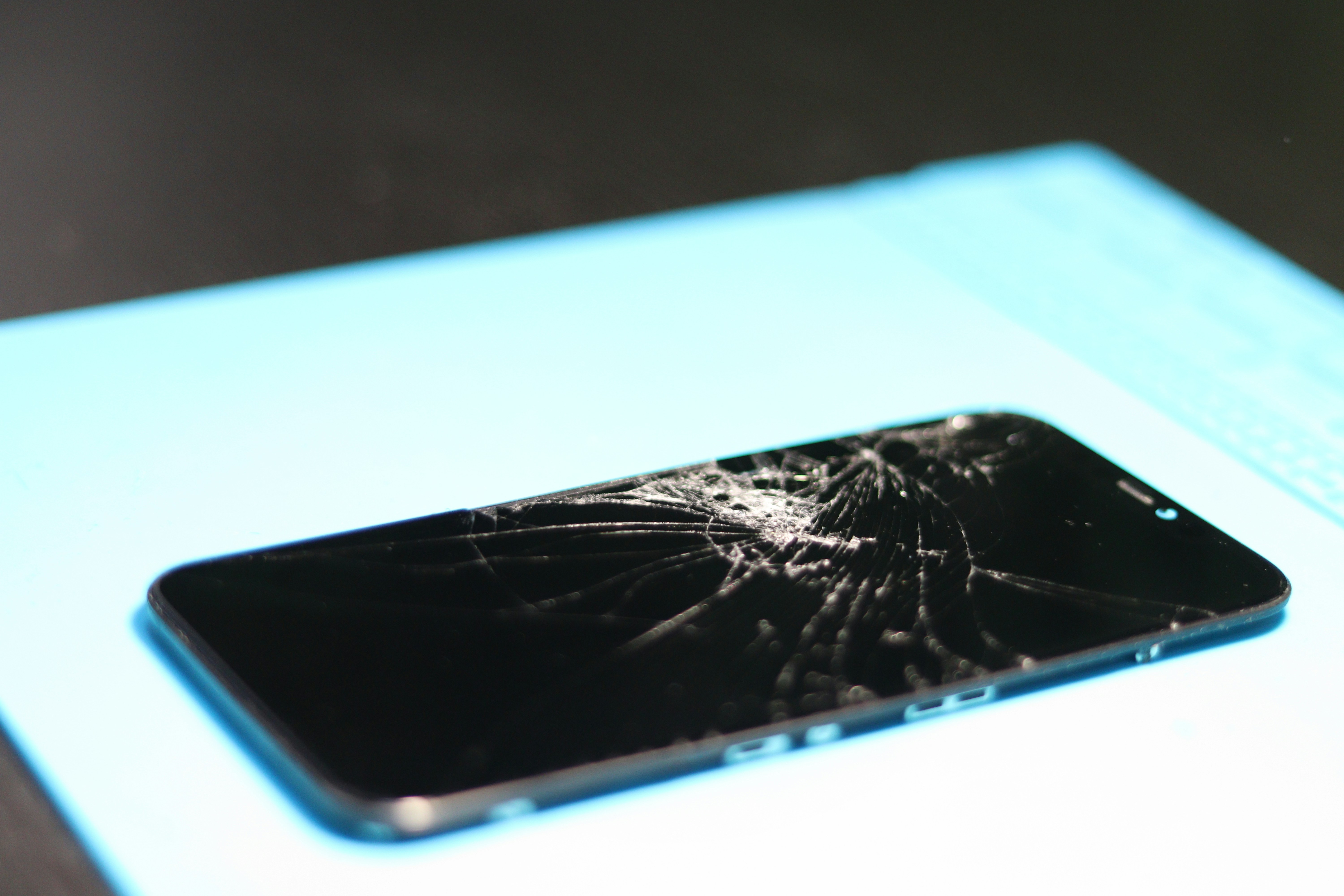 Broken smartphone screen on a blue mat.