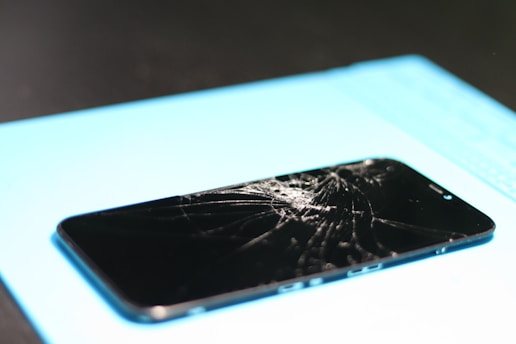 Broken smartphone screen on a blue mat.