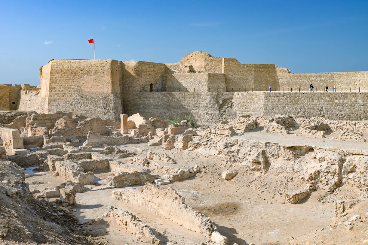 Here is a caption: ancient ruins in bahrain with a fortress.