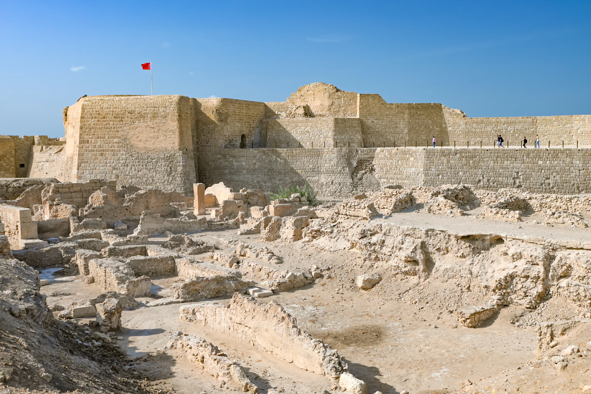 Here is a caption: ancient ruins in bahrain with a fortress.