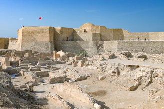 Here is a caption: ancient ruins in bahrain with a fortress.