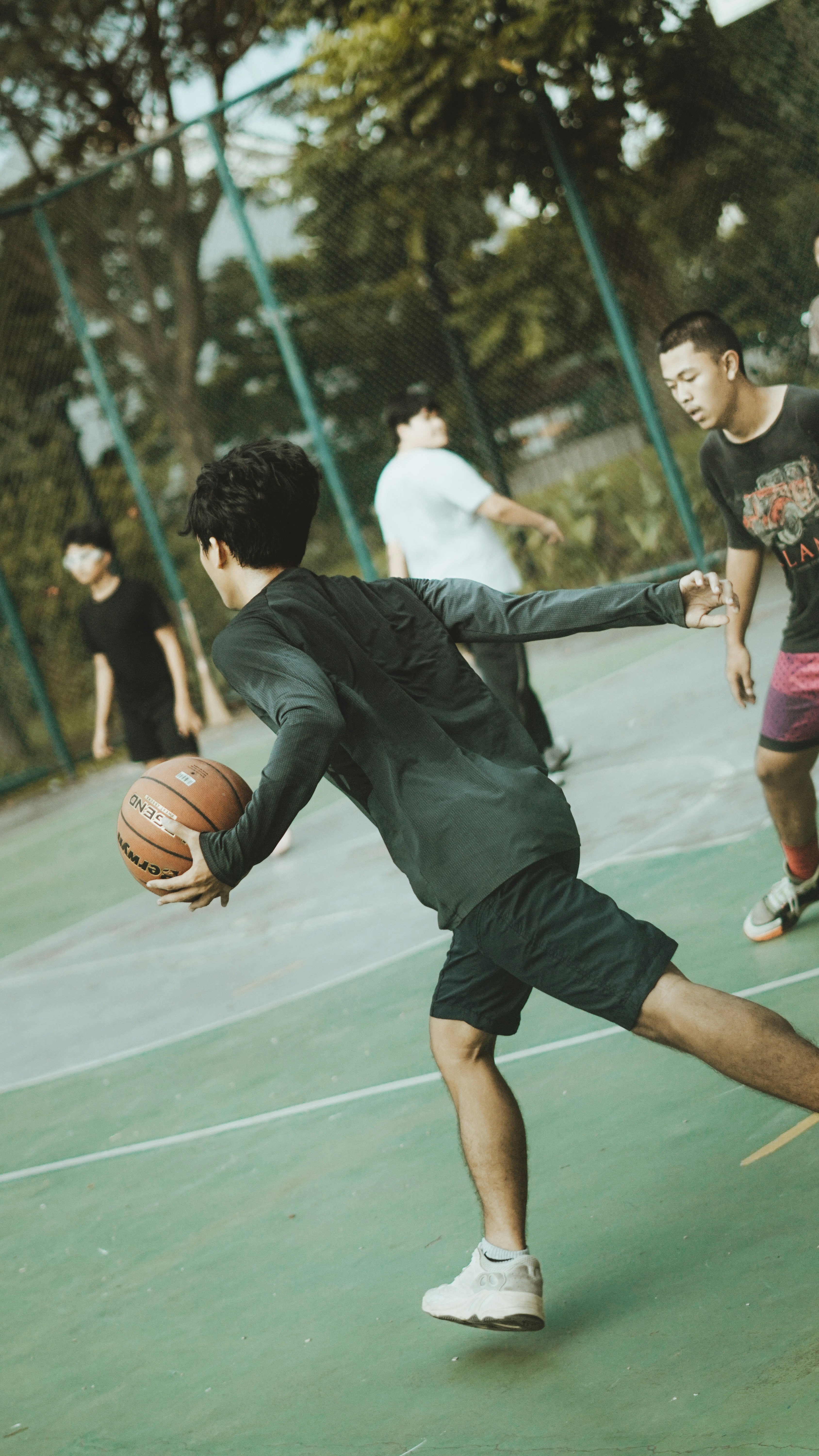 A group of people are playing basketball outdoors.