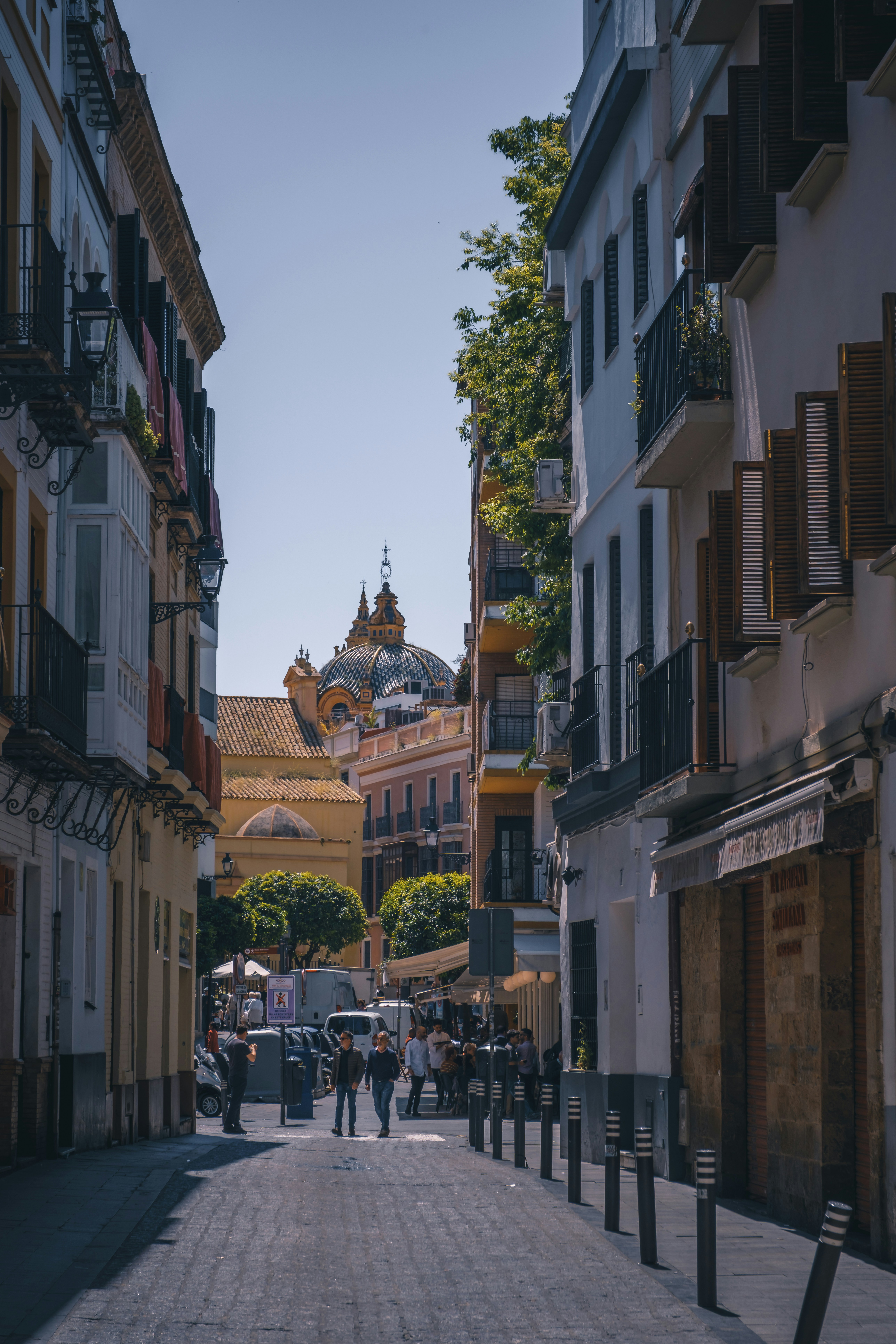 A narrow, european street with a cathedral at the end.