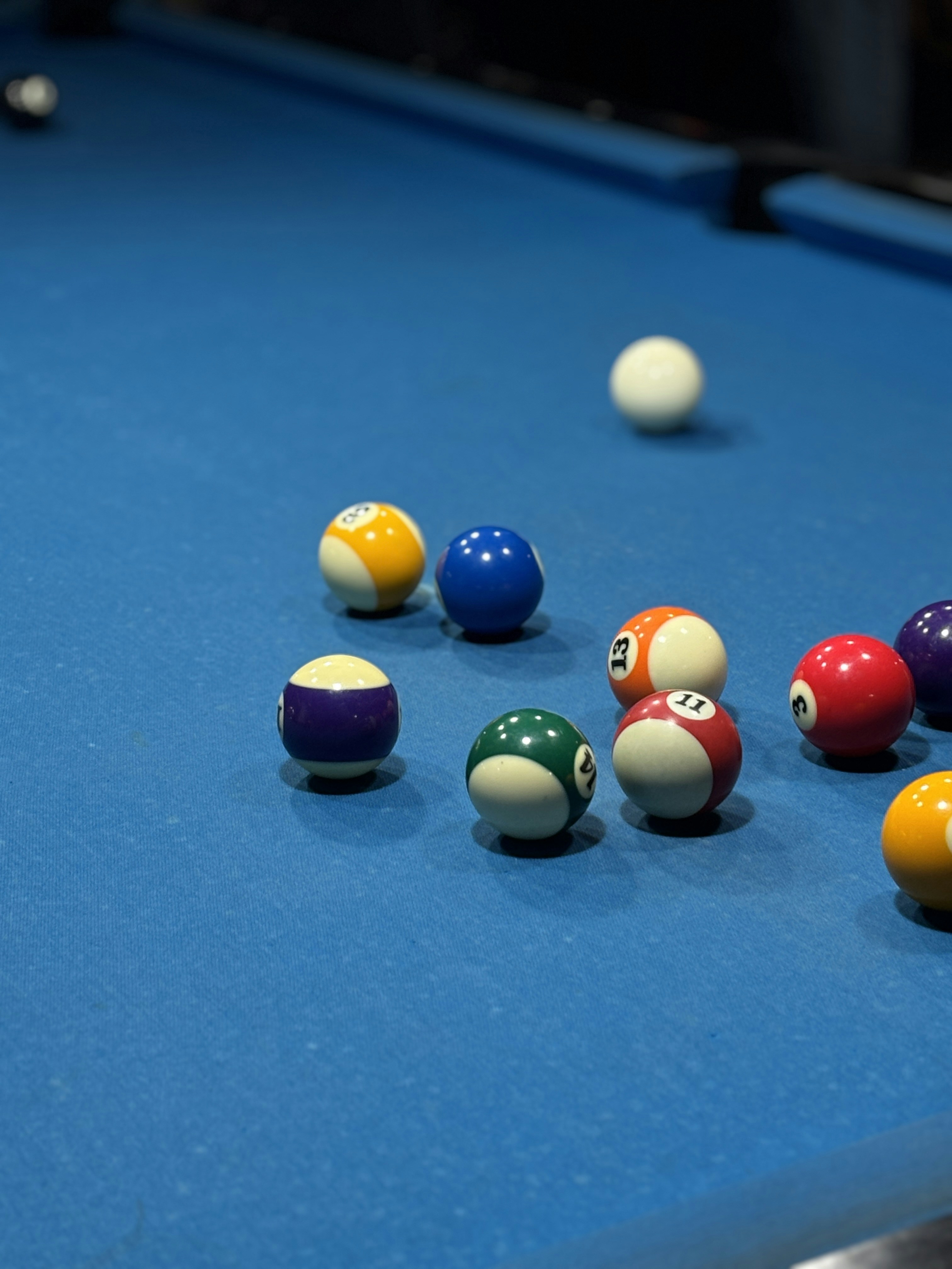 Pool balls are scattered on a blue pool table.