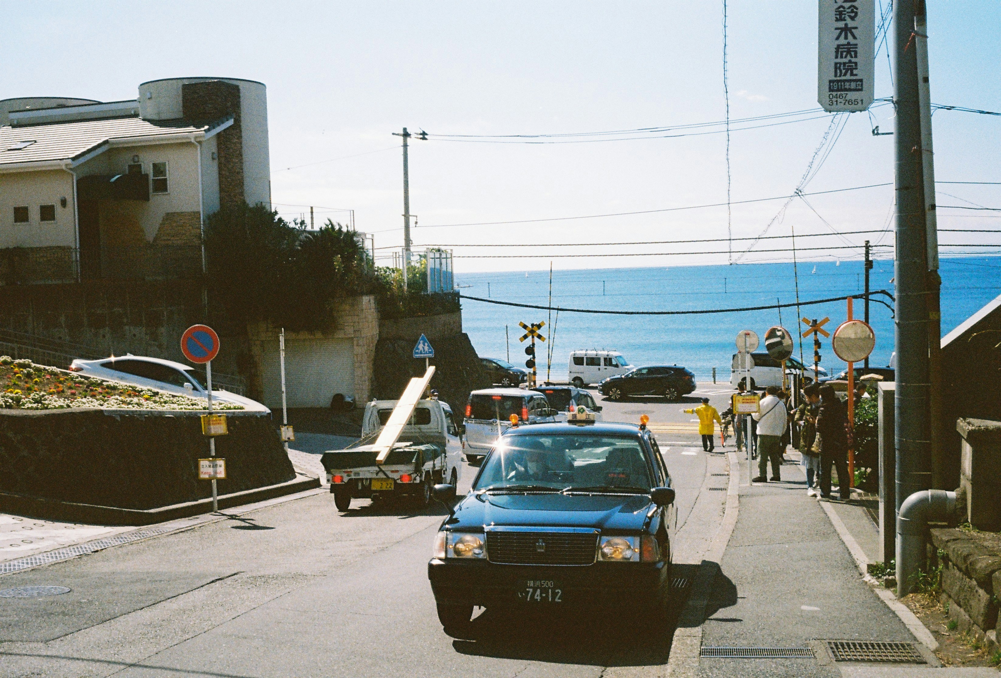 A coastal street scene with vehicles and people.