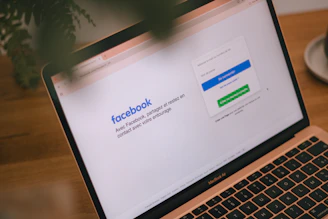 A laptop displays the facebook login page