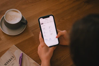 Checking finances on a phone with coffee