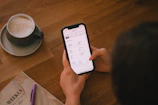 Checking finances on a phone with coffee