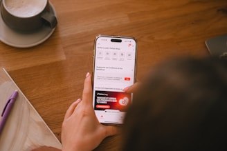 A person is using their phone at a table.