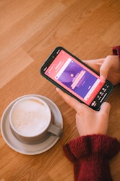 Someone is using their phone next to coffee.