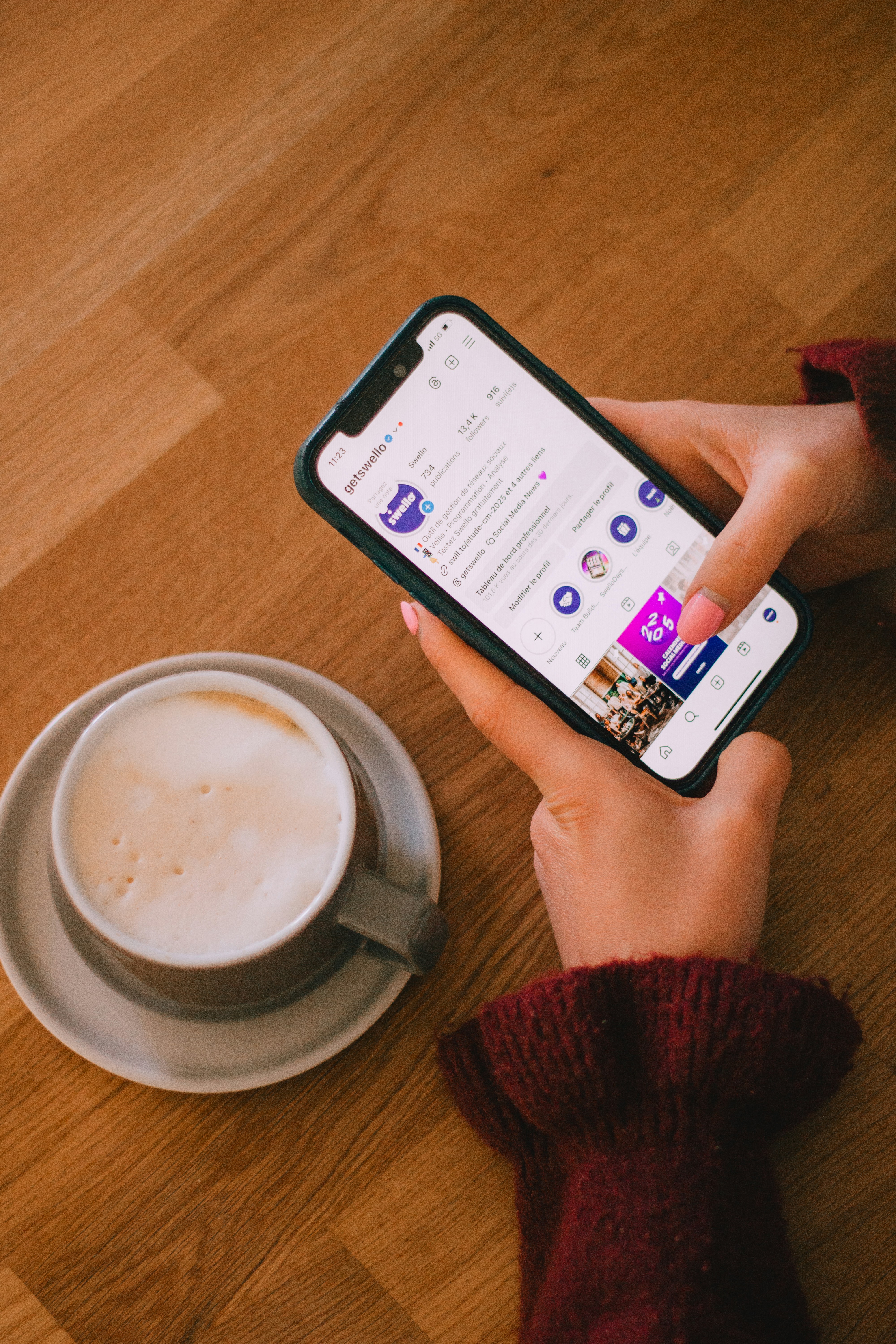 La persona usa el teléfono cerca de una taza de café.