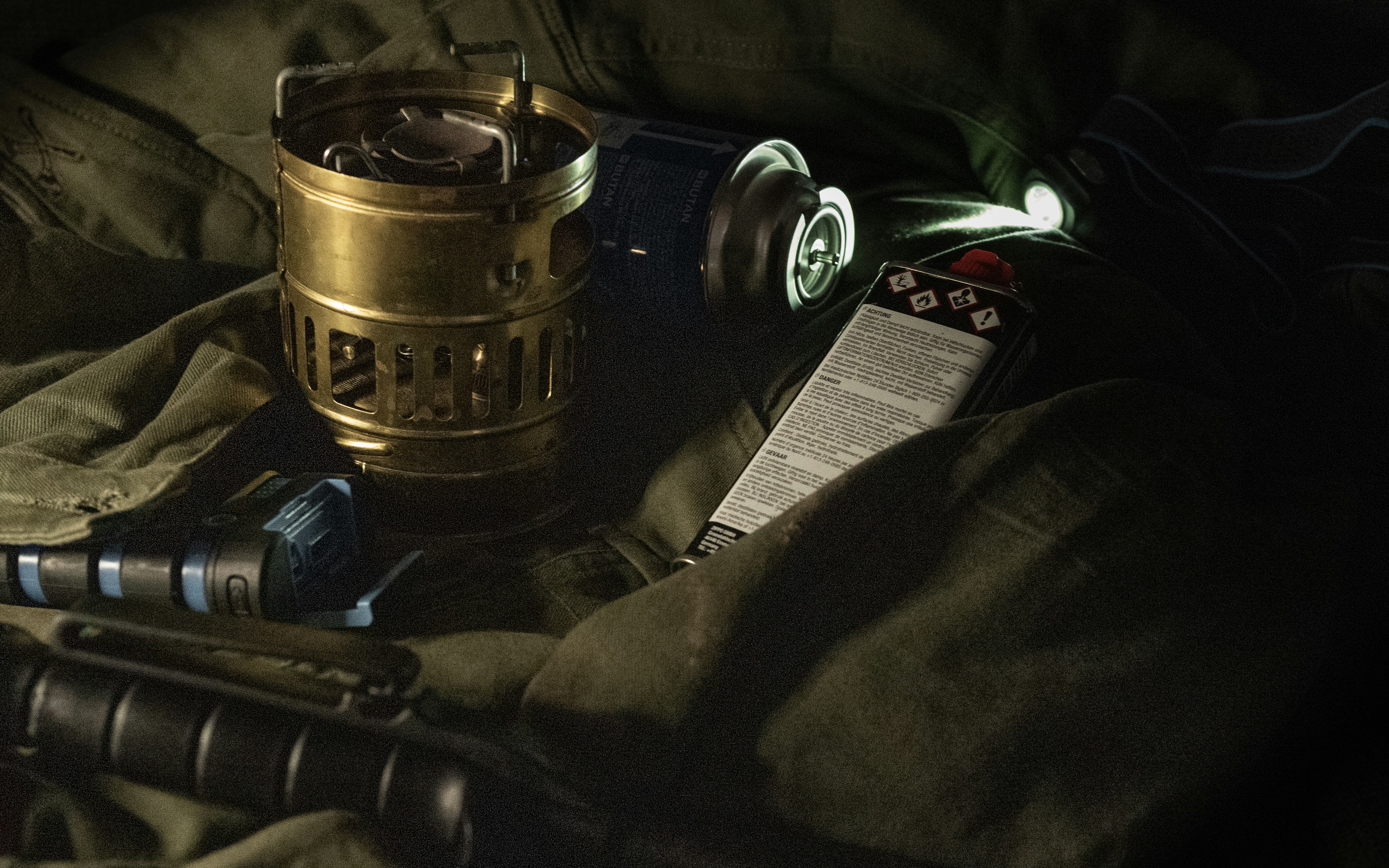 Powerbank, petrol stove, flashlight and other tools on olive canvas