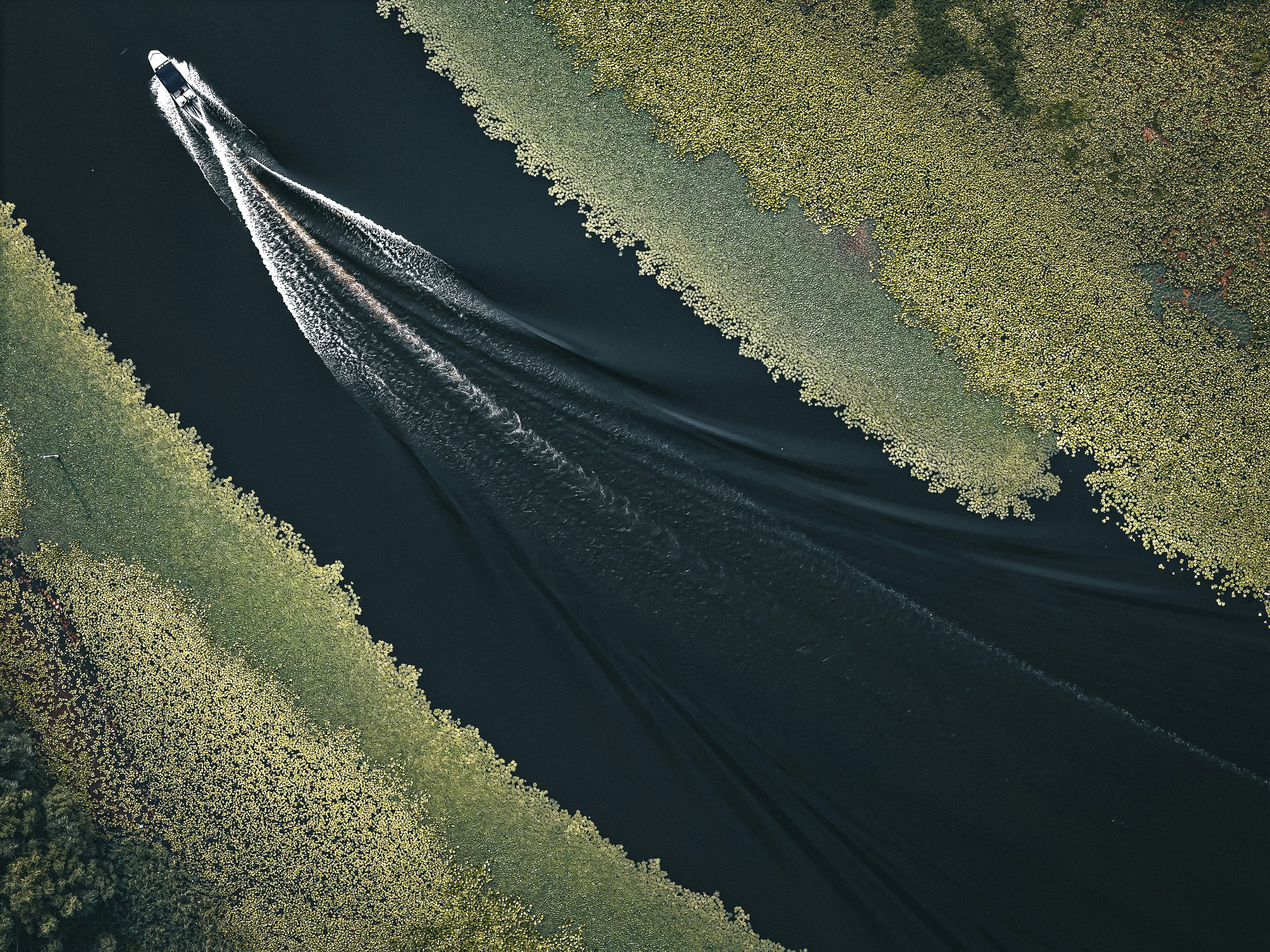 A boat leaves a wake in a narrow waterway.