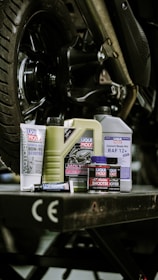 Motorcycle fluids and supplies are arranged under a bike.