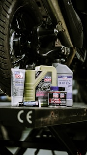 Motorcycle fluids and supplies are arranged under a bike.