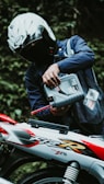 A motorcyclist is pouring oil into their motorcycle.