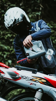 A motorcyclist is pouring oil into their motorcycle.