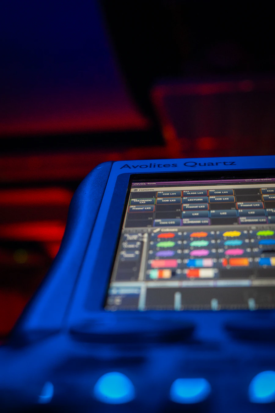 Lighting control console glowing in a dark booth