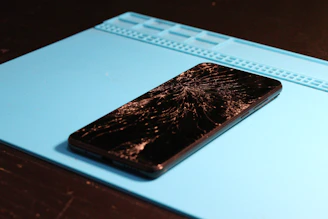 A smartphone with a shattered screen lies down.