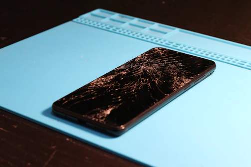 A smartphone with a shattered screen lies down.