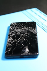 Broken smartphone screen on a repair mat.