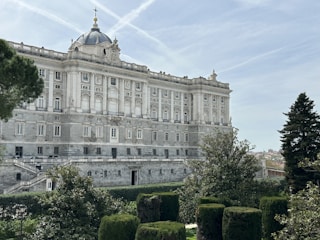 The royal palace of madrid is surrounded by trees.