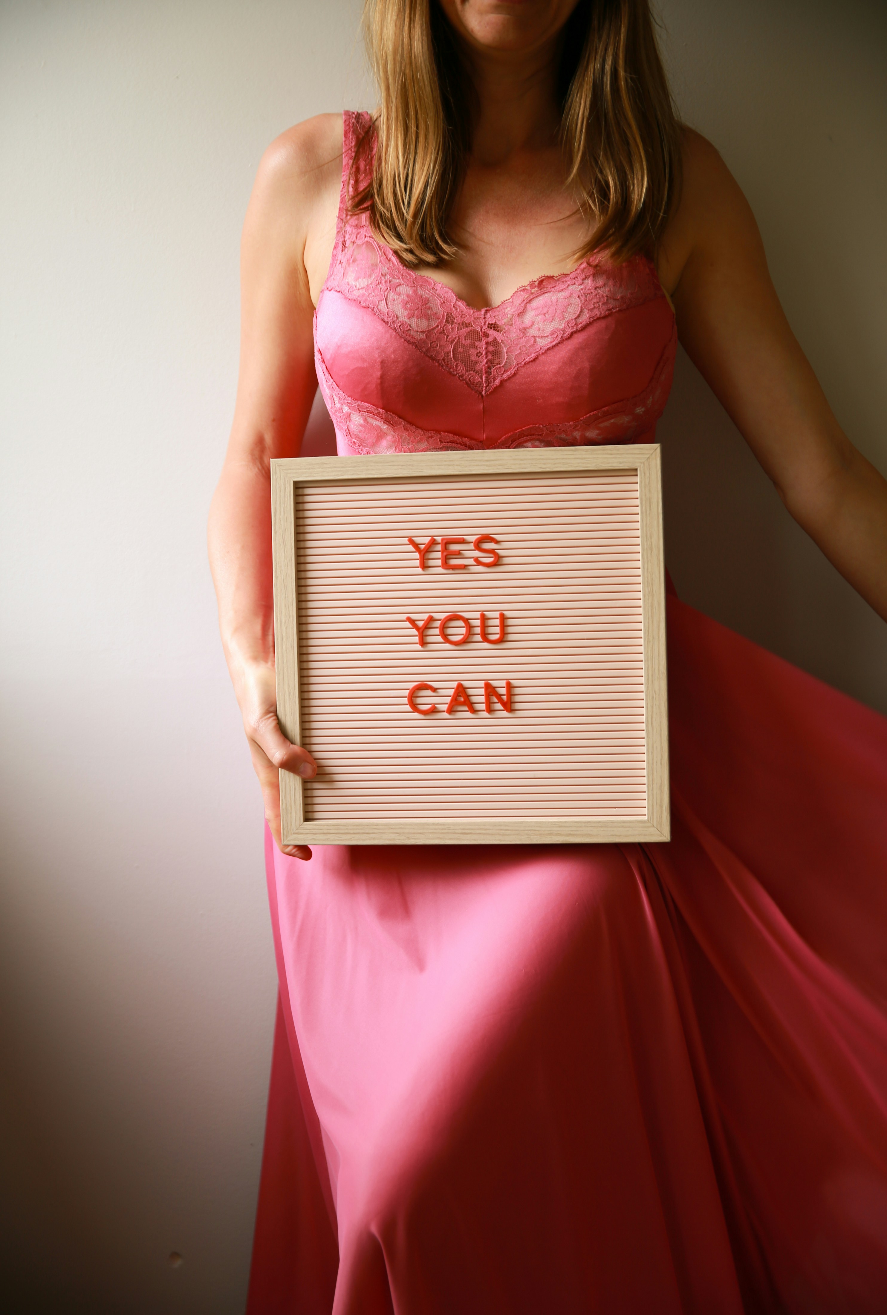 A woman holds a sign saying "yes you can."