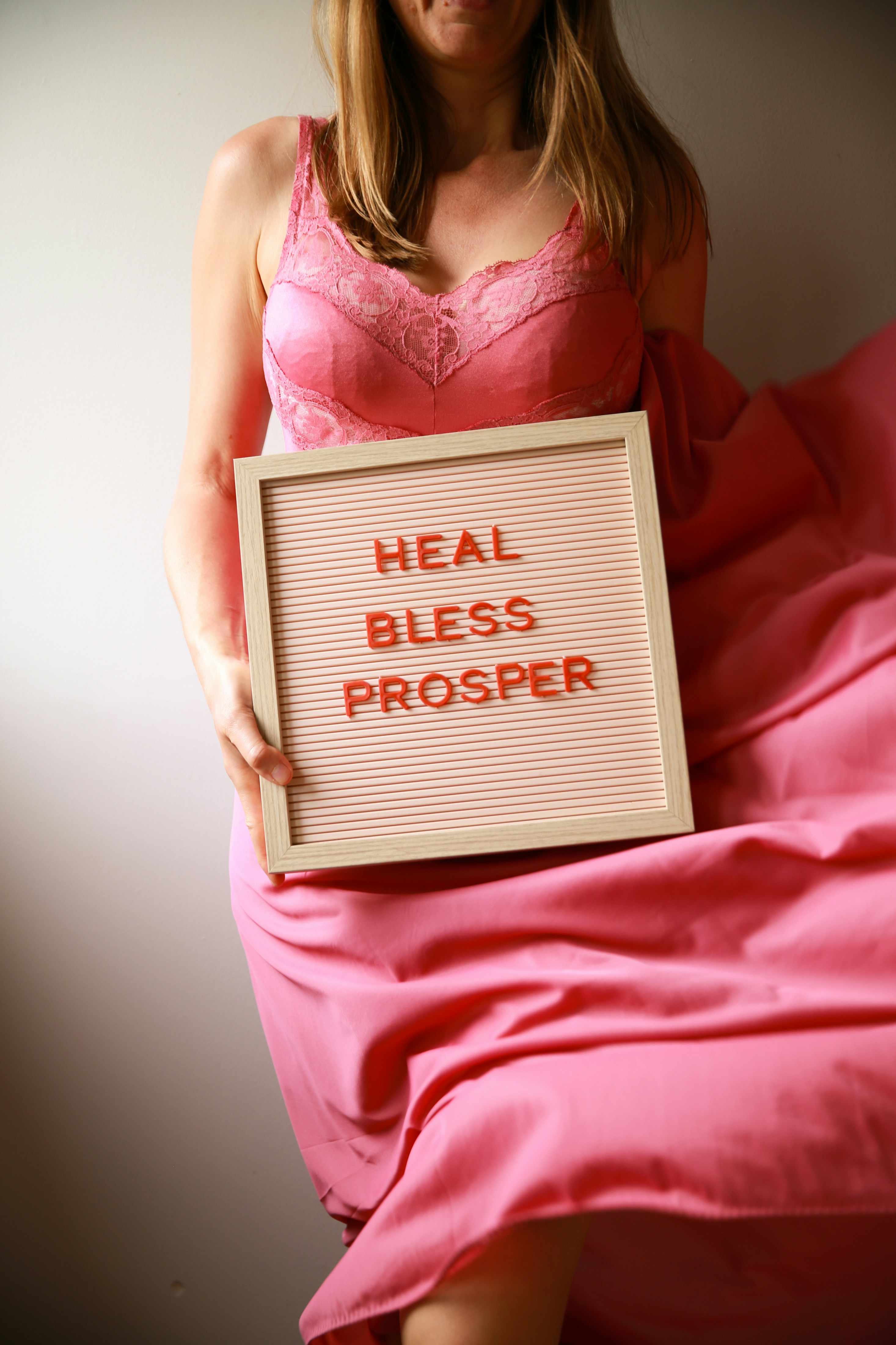Woman holds a sign that says "heal, bless, prosper".