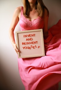 Woman holds sign, encourages self-invention.