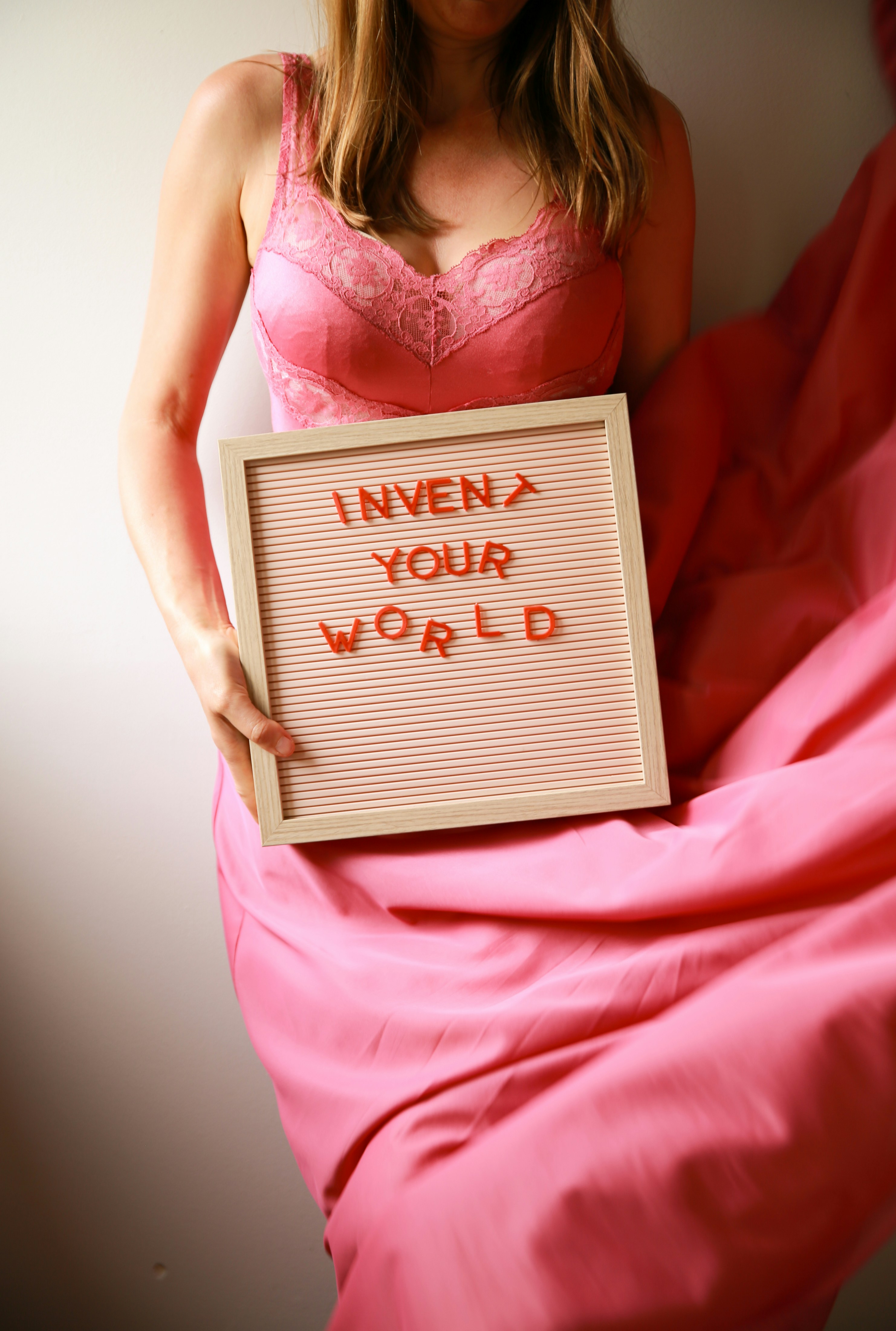 Woman holds sign that says "invent your world".
