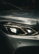 Headlight of a silver car shines brightly.