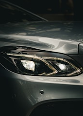 Headlight of a silver car shines brightly.
