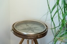 A compass sits on a wooden tripod.