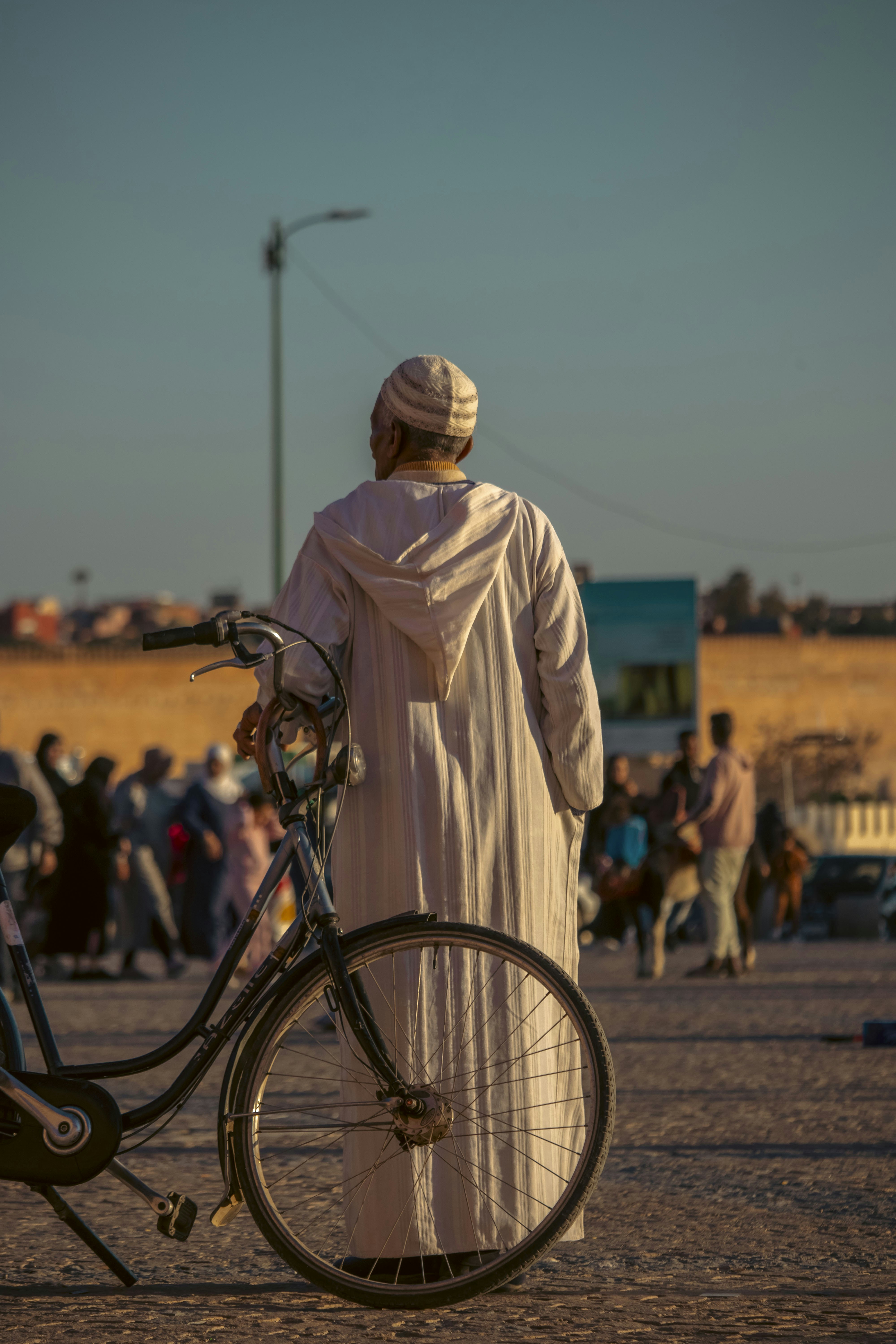 Um homem em traje tradicional com uma bicicleta.